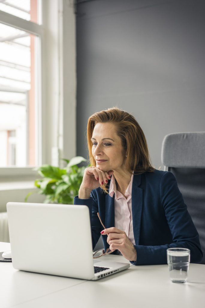 Businesswoman sitting in office, working on laptop